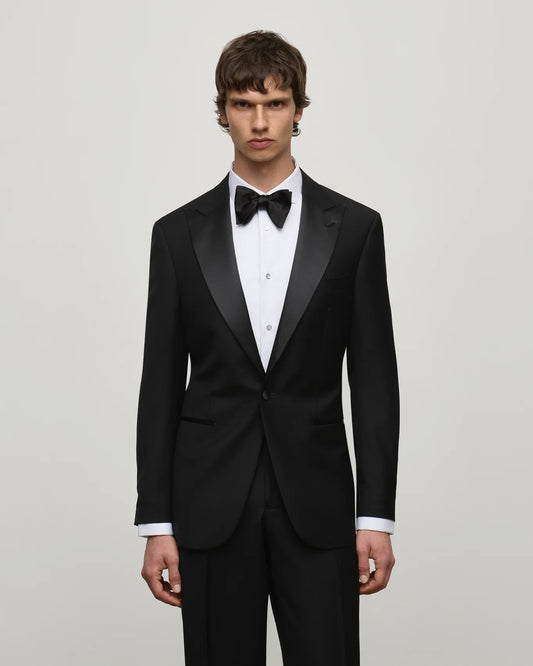 AIKO Black Wool Tuxedo Jacket with satin peak lapels, paired with a white shirt, silver studs, and a black silk bowtie.
